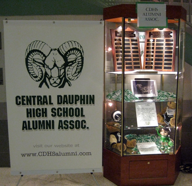 Our display case in the CDHS aud/gym lobby. The Alumnus of the Year perpetual plaque is on the top shelf, along with the School Spirit Scholarship plaque.