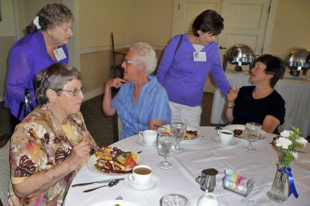 Carolyn (Kludas) Drake eats while Ora Lee (Ault) Kapp, Carolyn Bruce, Sharon (Blomquist) Moomaw, and Beatrice (Beard) Groom chat