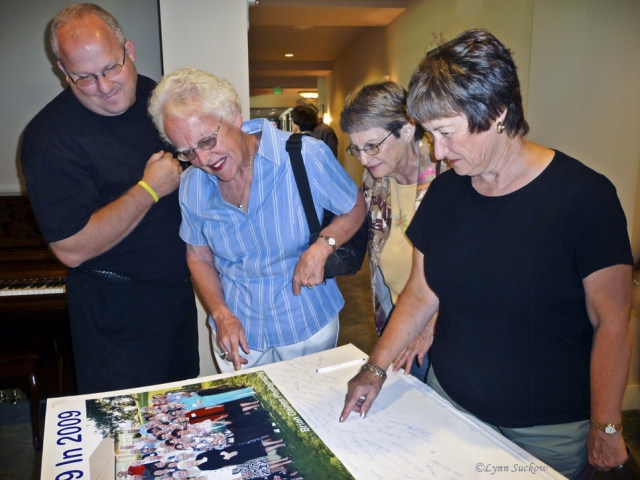 Brian Gaines (photographer), Carolyn Bruce, Carolyn (Kludas) Drake, and Beatrice (Beard) Groom looking at 50th reunion class photo of the 59ers