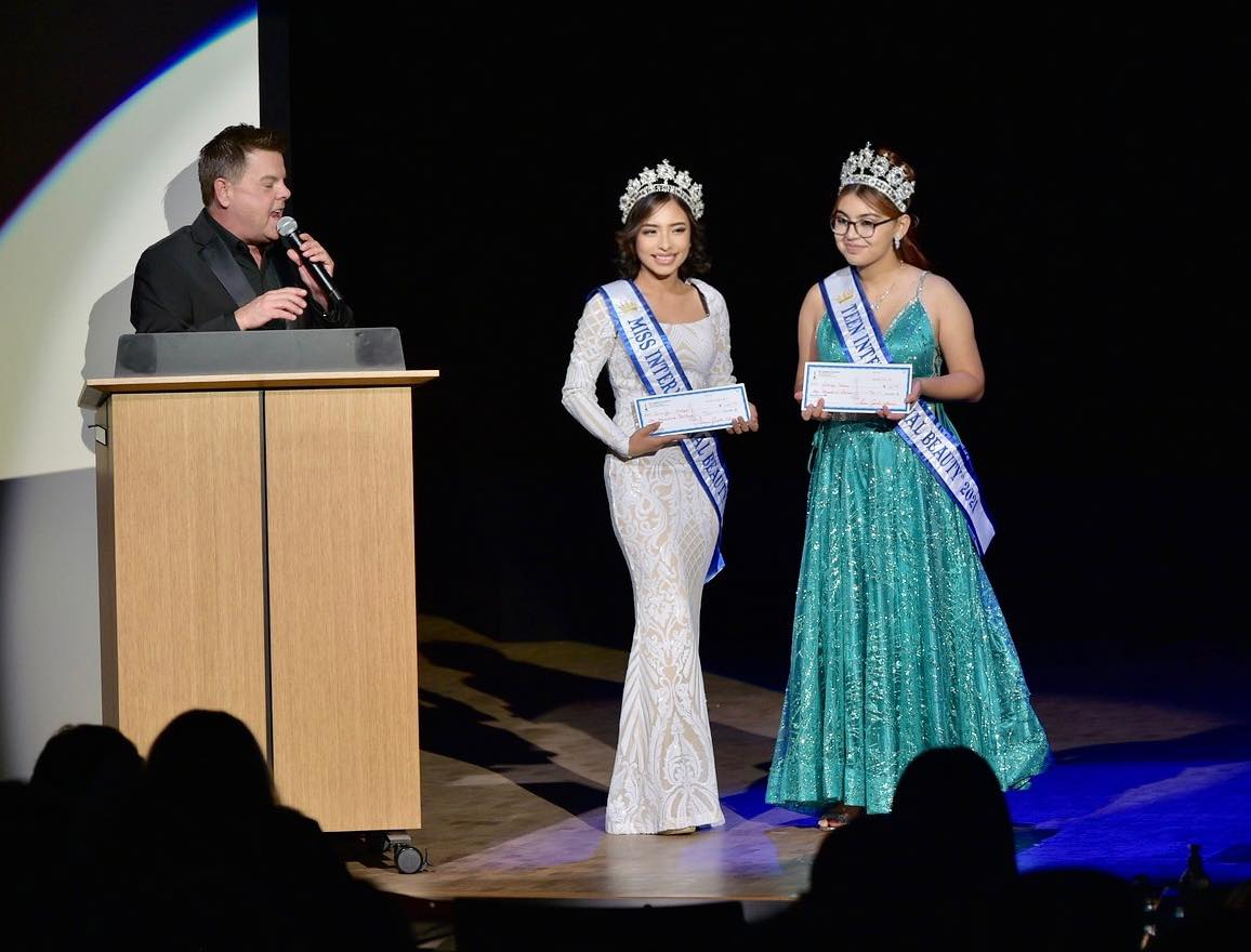 Miss International Beauty and Teen International Beauty receiving their check on-stage at the Ms. International Pageant in 2021.